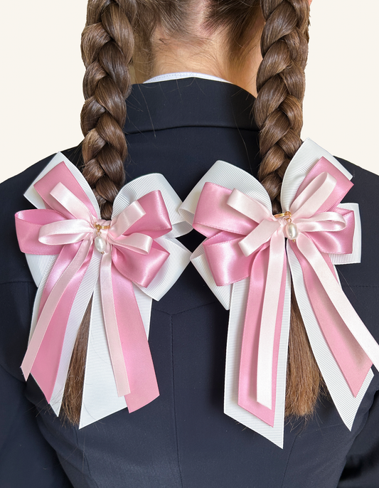 Pink Pearl horse show bows worn on two braids against a navy riding jacket