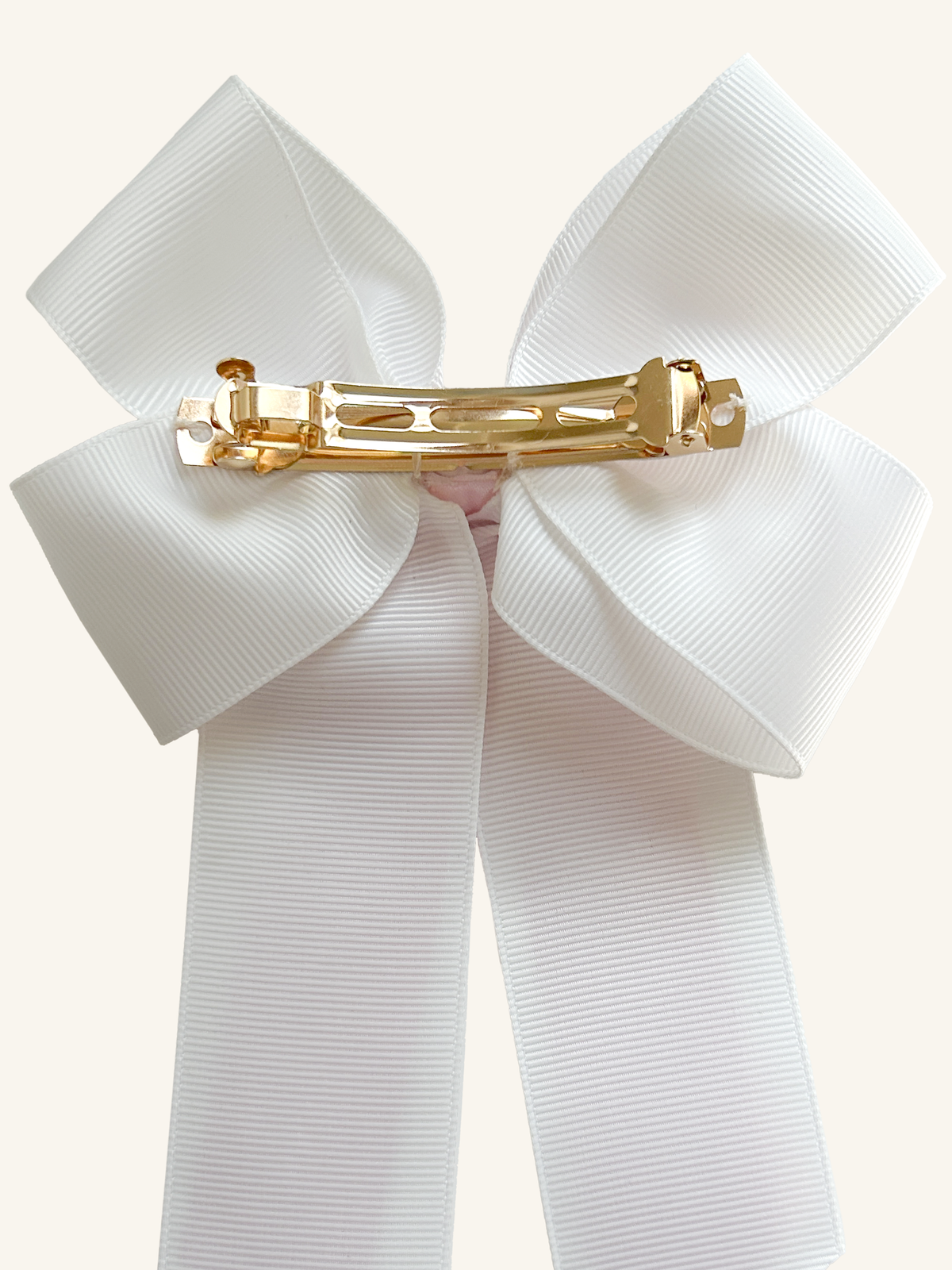 Back of a Pink Pearl horse show bow showing the gold French barrette